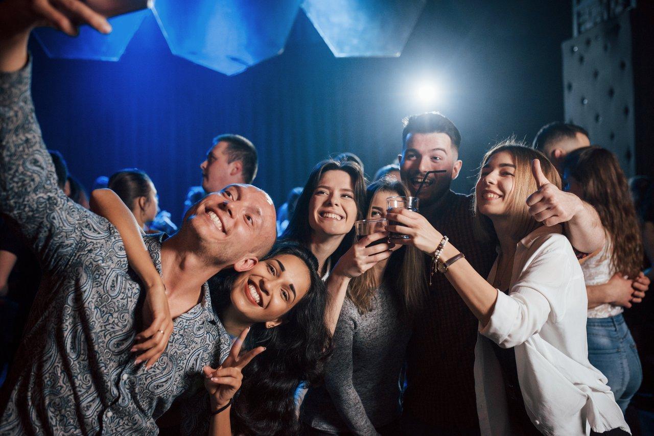 L'éclat du flash électronique illumine les sourires en discothèque, capturant la joie nocturne.