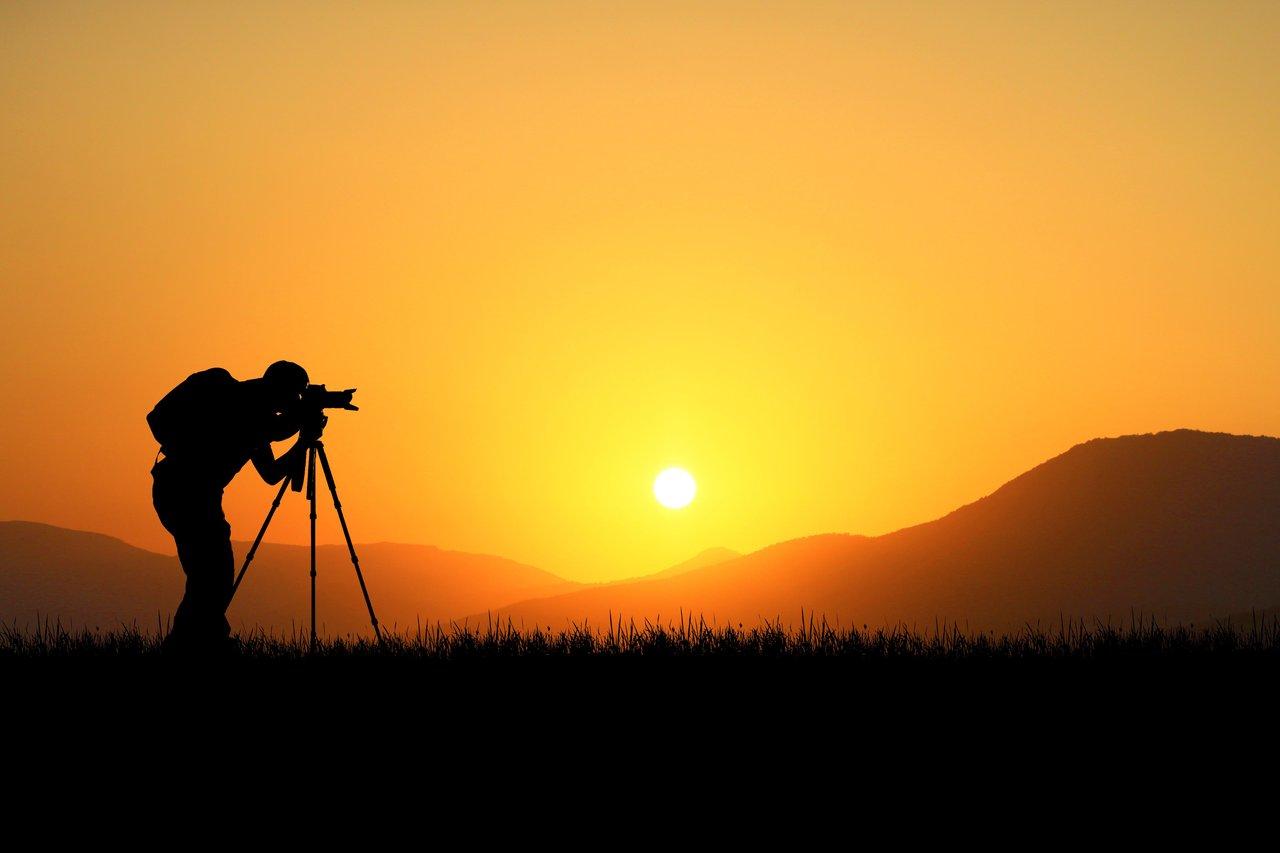 Photographe professionnel capturant des images dans un champ avec son équipement.